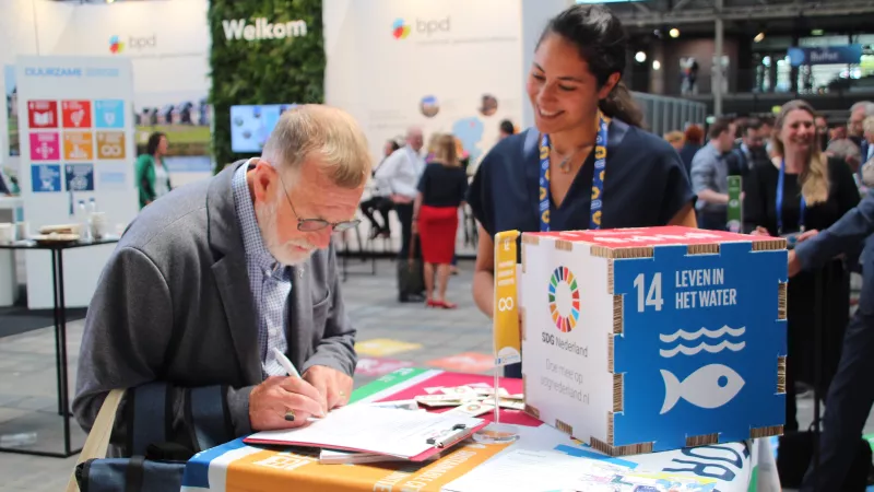 Een man schrijft iets op bij de Global Goals-stand
