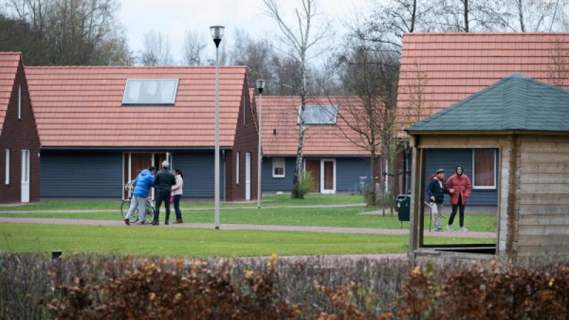 Mensen lopen buiten op terrein van asielzoekerscentrum