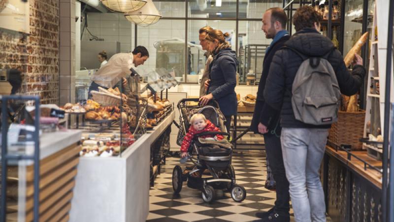 klanten en winkelier bij toonbank levensmiddelenwinkel