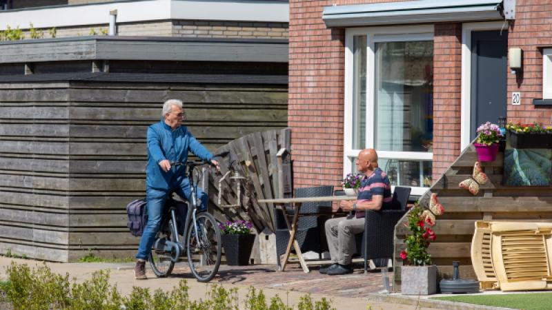 2 mannen praten met elkaar in een voortuin