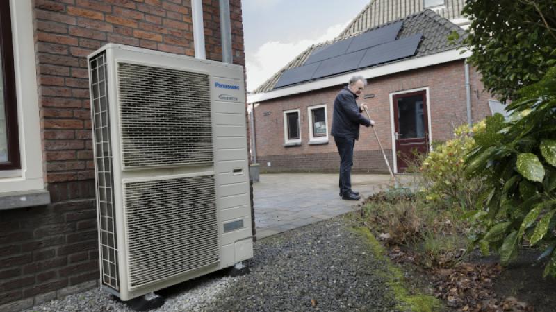 Man veegt tuin aan naast een warmtepomp