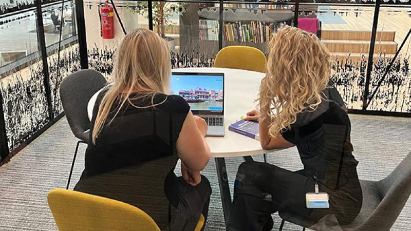Fanny Brongers en Evelien van Wijngaarden van de gemeente Nissewaard zitten samen aan tafel achter een laptop.