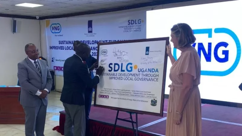 Oegandese man zet zijn handtekening op een bord waarop staat SDLG Uganda