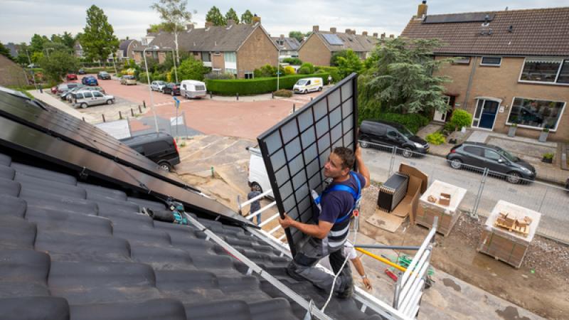 Monteur tilt een zonnepaneel het dak op