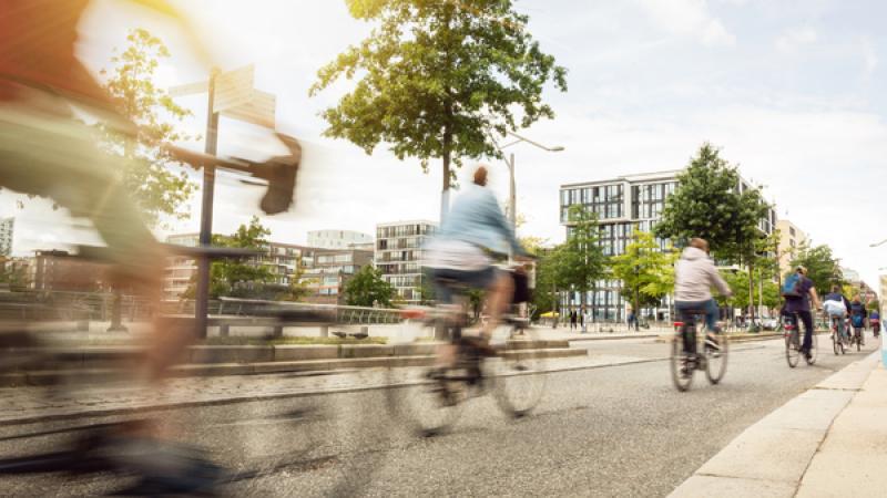 Fietsers rijden voorbij met kantoorgebouwen op de achtergrond