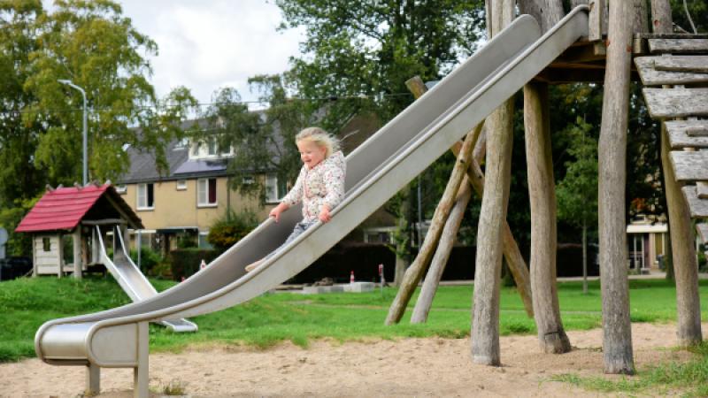 Kind gaat in een speeltuin van de glijbaan