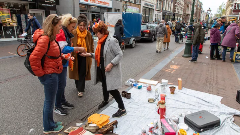 vrouwen met oranje sjaals om bekijken handelswaar op een vrijmarkt
