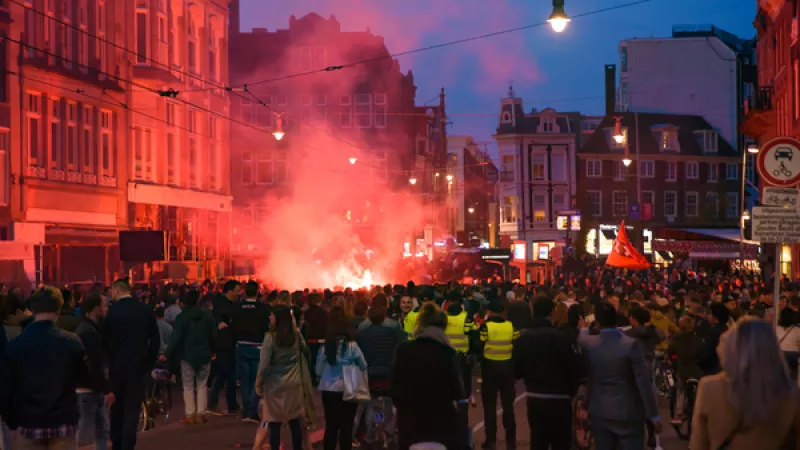 rel in binnenstad Amsterdam tijdens avonduren: menigte bij straatvuiur