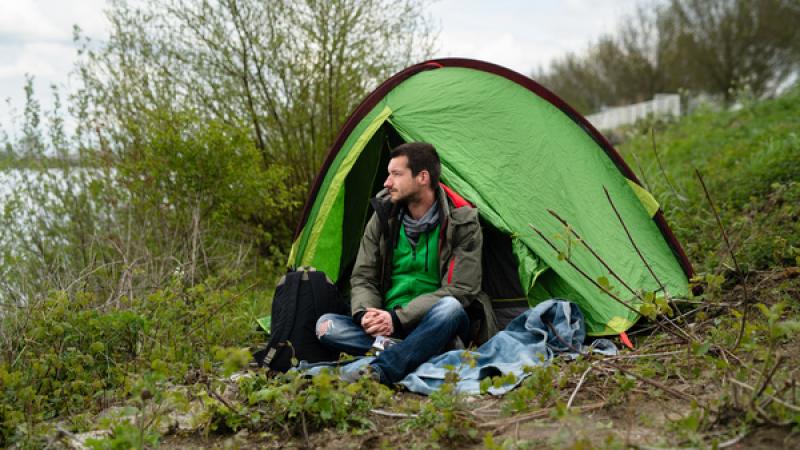 man zit voor een tentje aan de waterkant