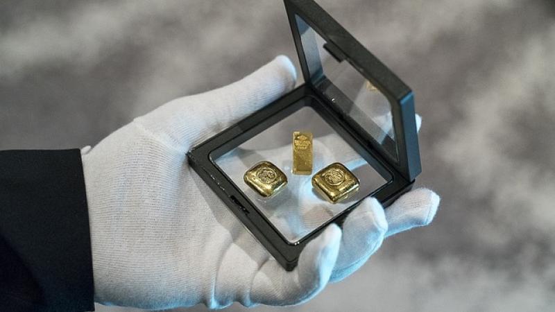 gehandschoende hand toont doosje met gouden sieraden