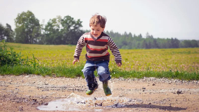 kind speelt buiten: sprint in een regenplas