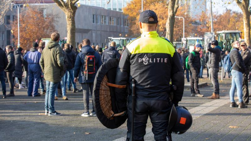 politieagent met wapenschild kijk toe bij demonstratie boeren