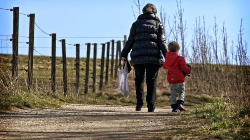 Volwassene loopt hand in hand met klein kind
