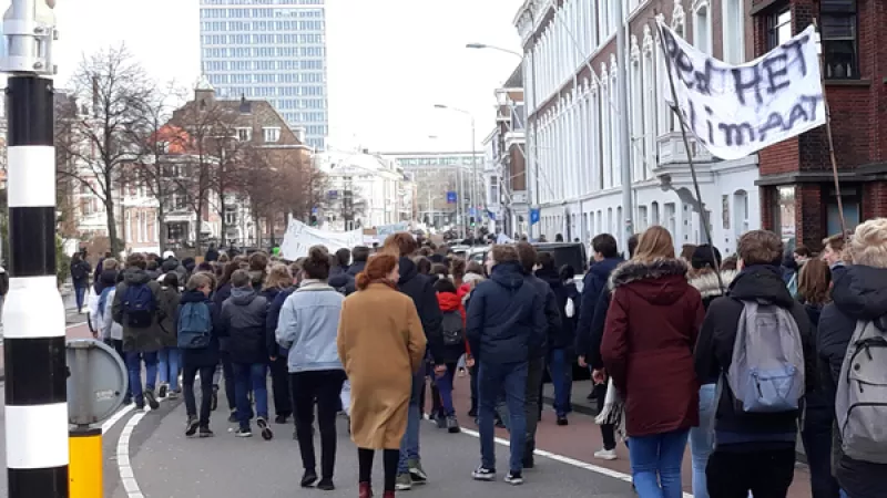 demonstratie in een straat in Den Haag, demonstraten op de rug gezien, zichtbaar is een spandoek met de tekst 'Red het klimaat'