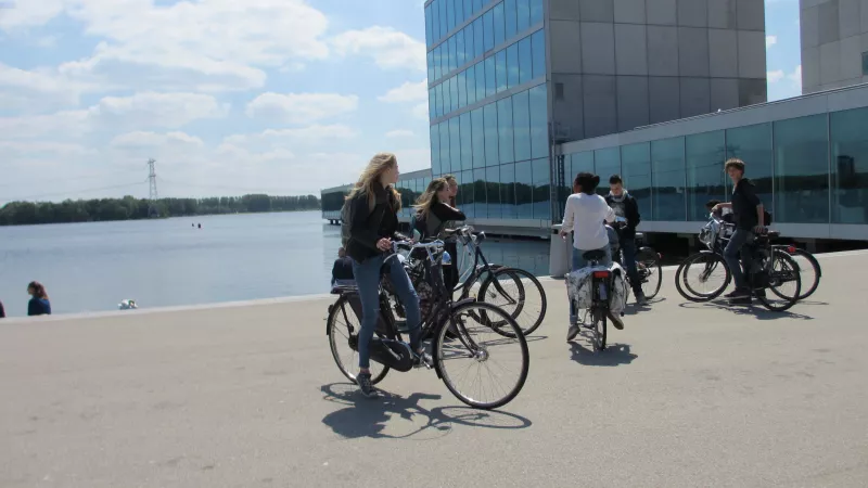 Fietsers voor een gebouw langs het water