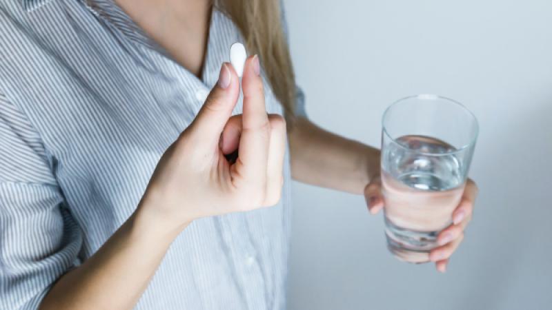 Vrouw met paracetamol en waterglas