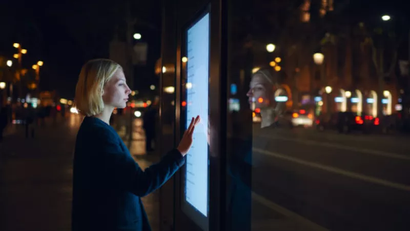 Vrouw gebruikt op straat een display met touchscreen 