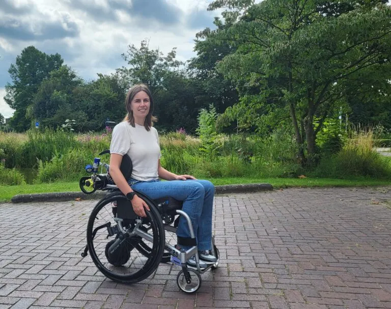 celine hermans in haar roelstroel op straat met grasveld, bomen en planten op de achtergrond